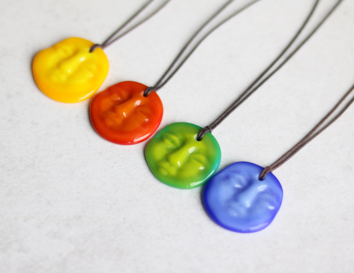 Bright, colorful necklace with four different colored pendants on a grey background