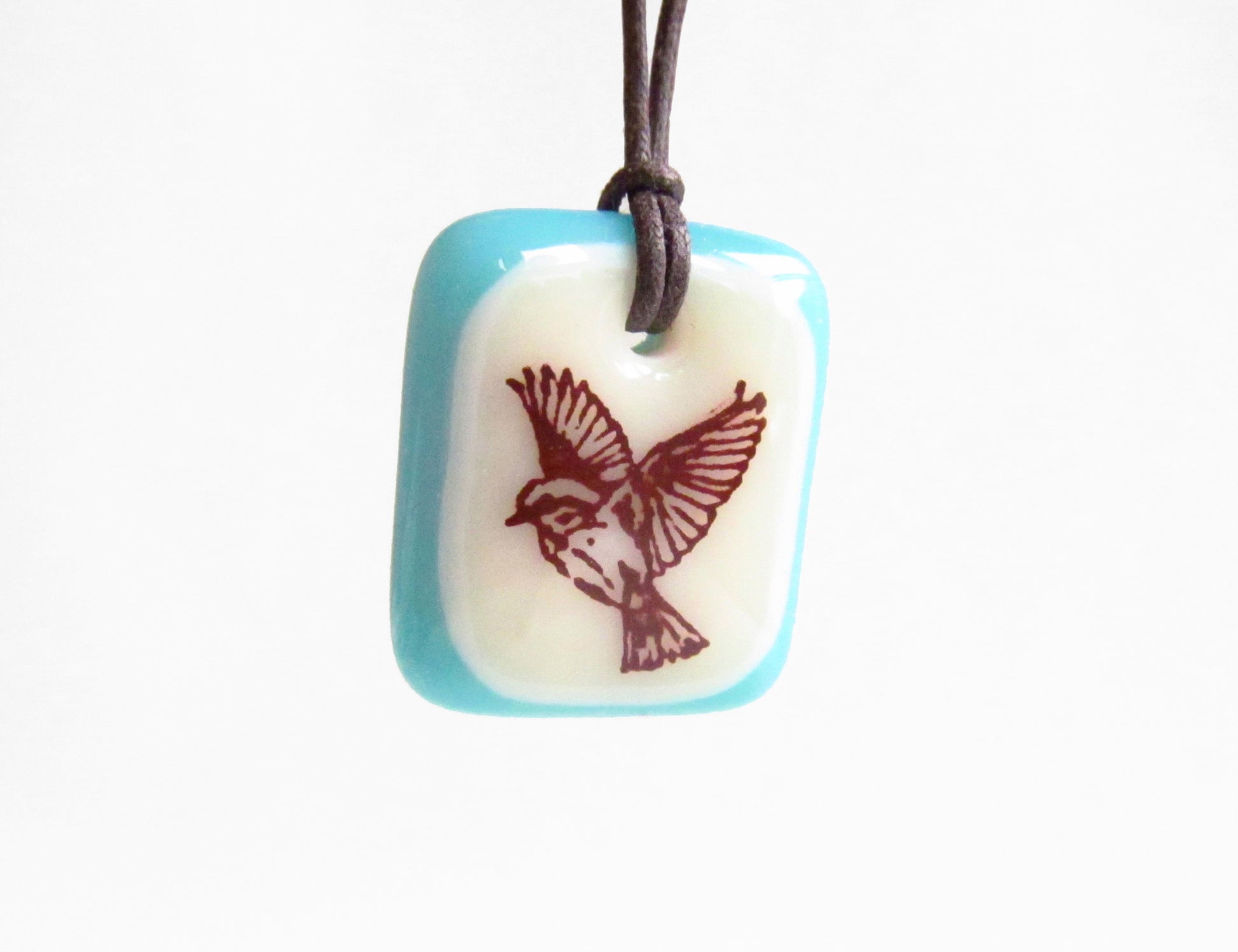 Flying bird necklace in blue and cream glass. 