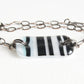 Black and white striped glass bracelet on adjustable bronze chain.