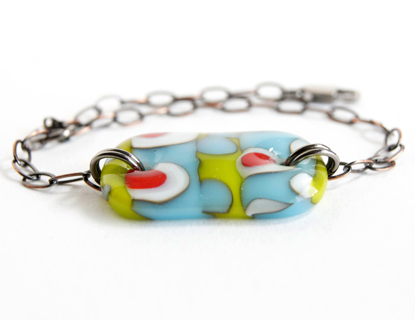 A fun abstract glass bracelet in green and blue with red dots.