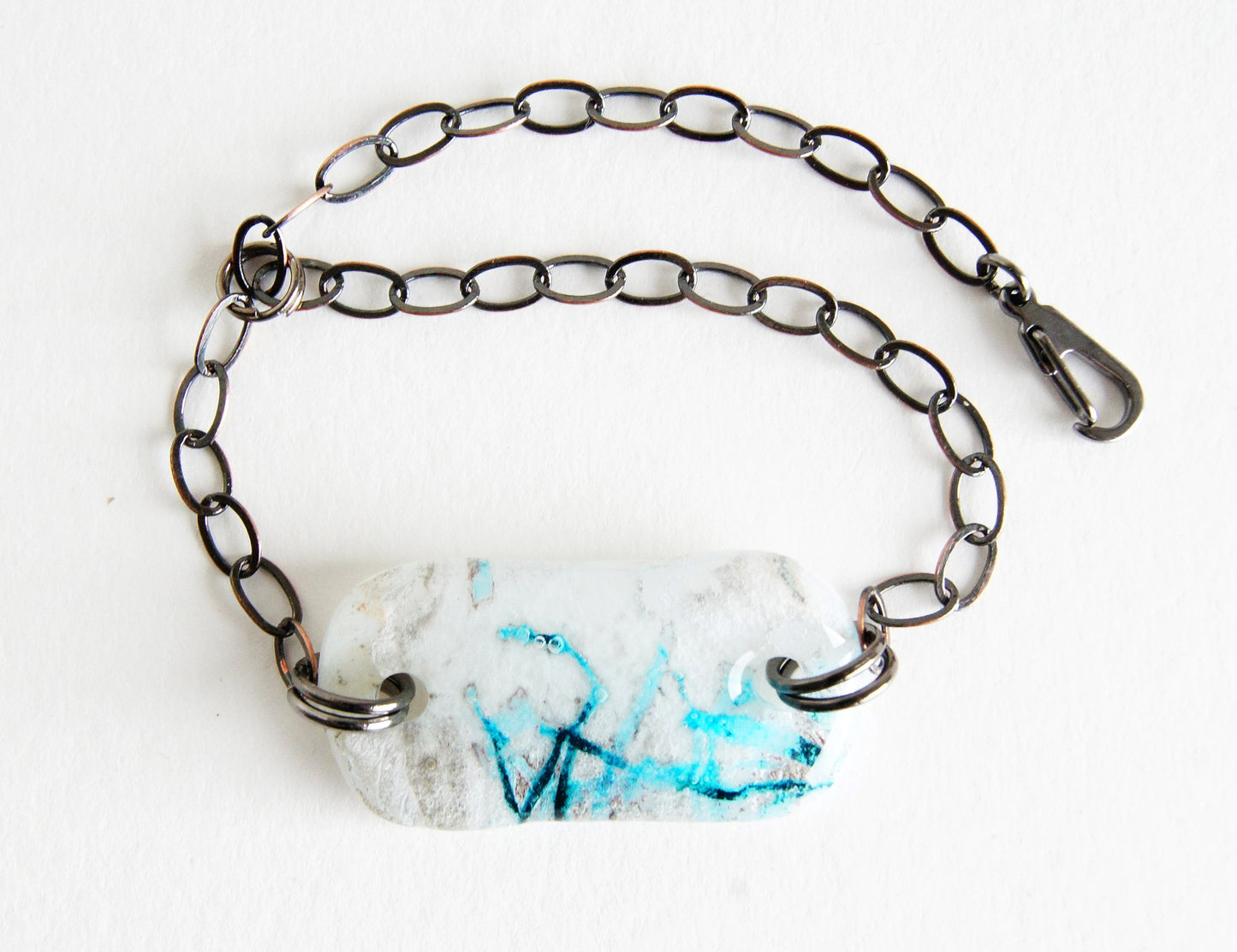 Adjustable chain bracelet with a white and blue abstract glass focal bead.