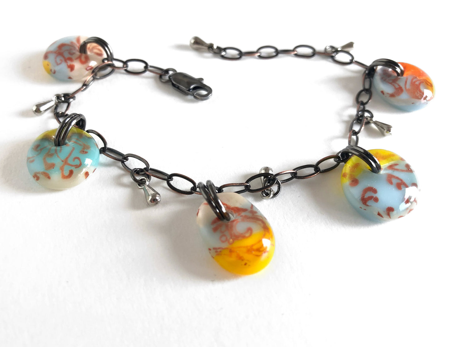 A fused glass bracelet with vintage style glass drops, filigree design and adjustable bronze chain.