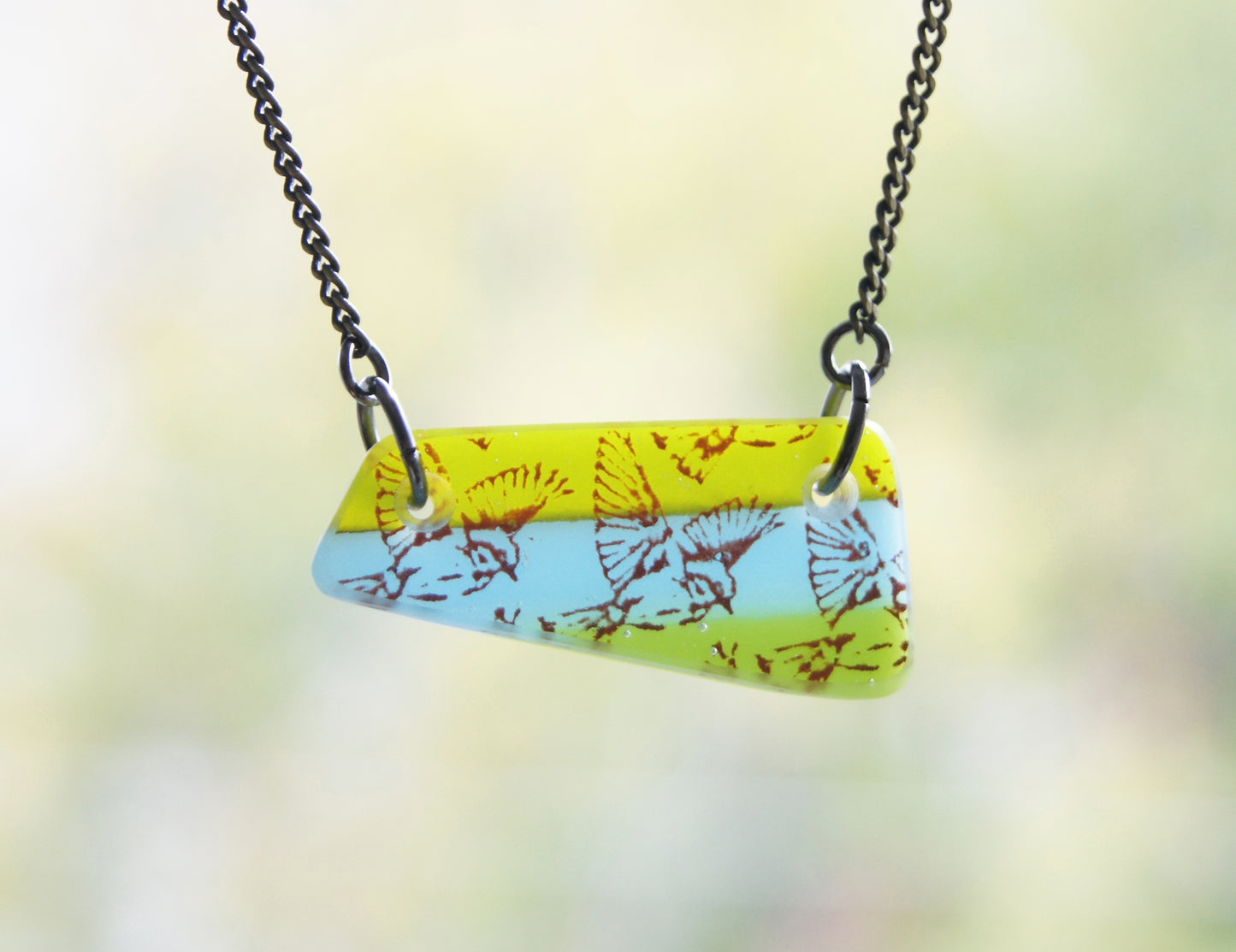Bird in flight illustration on colourful handmade necklace.