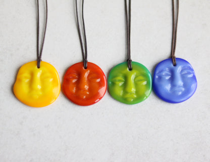 Four colorful face-shaped pendants on strings against a light background