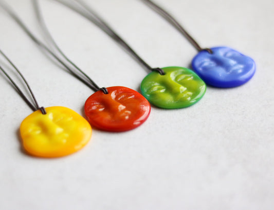 Four colorful necklaces with different colored pendants on a white background