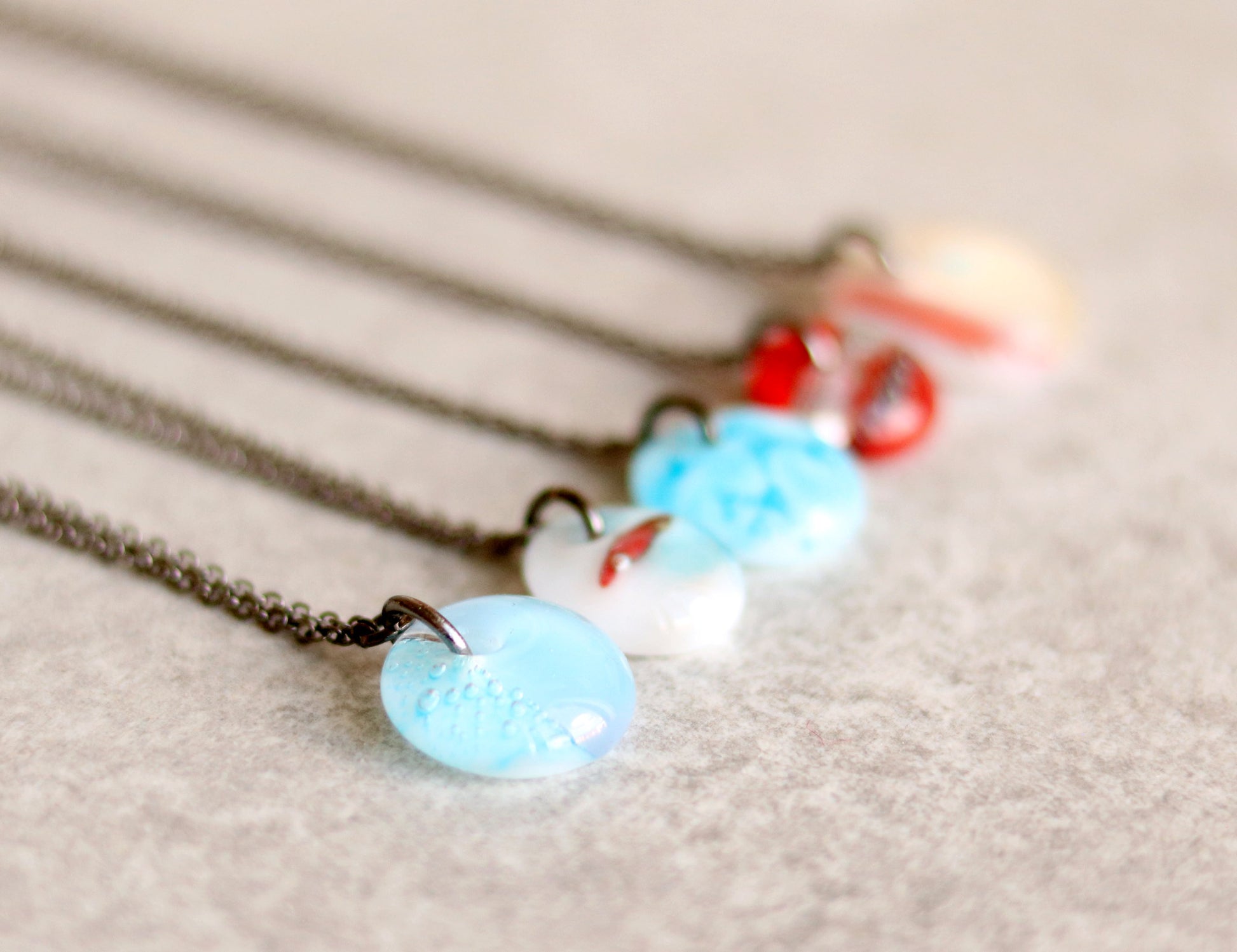 Necklaces with blue and red pendants on a light background