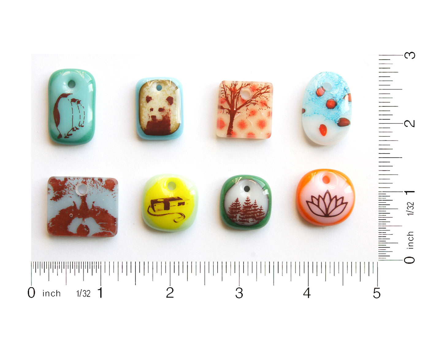Eight handmade glass pendants with ruler to show size. 