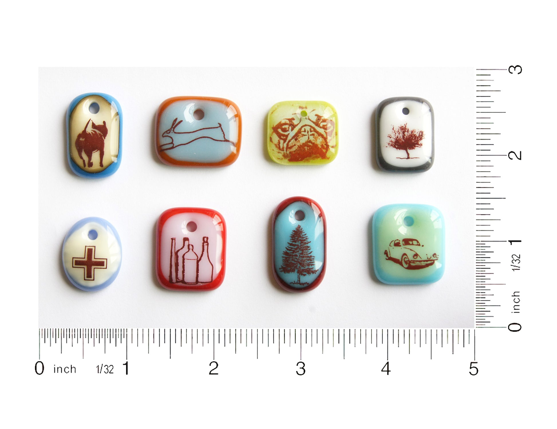Eight colourful glass pendants handmade by Leila Cools on grid with ruler guide