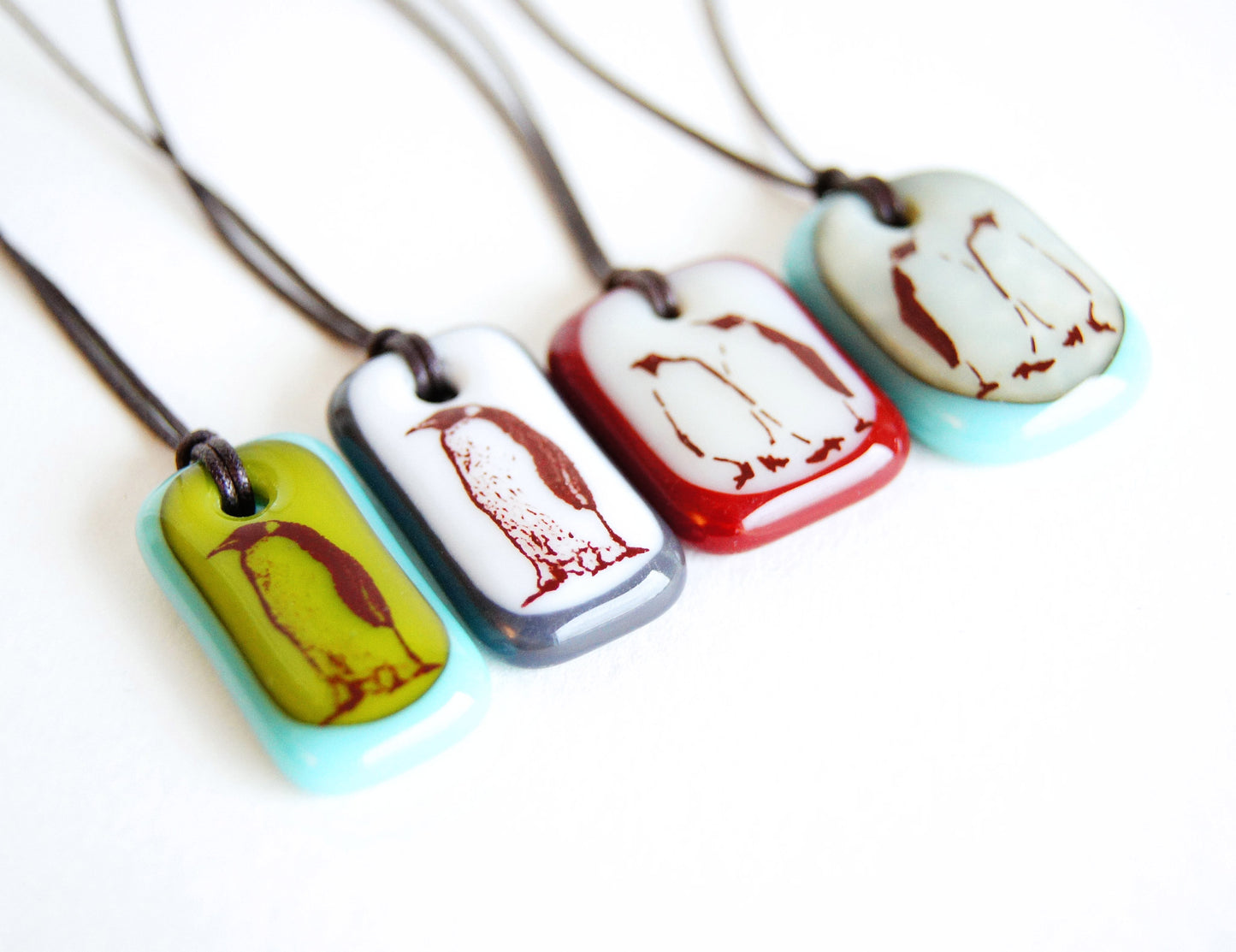 Illustration of one or two penguins fused onto a handmade glass pendant necklace.