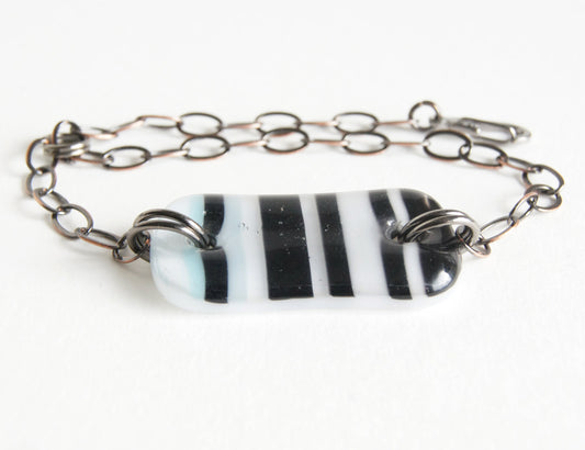 Black and white striped glass bracelet on adjustable bronze chain.