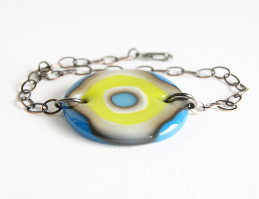 A fun bold glass and chain bracelet with a blue and green bullseye design.
