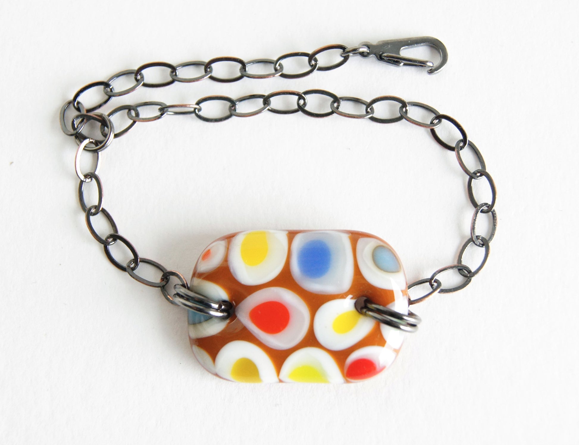 Circus inspired multicolor spotted glass bracelet with bronze chain.