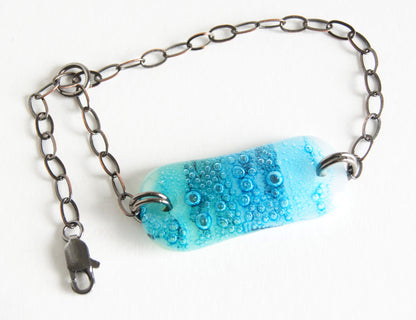 Adjustable bronze chain bracelet with beach blue fused glass.