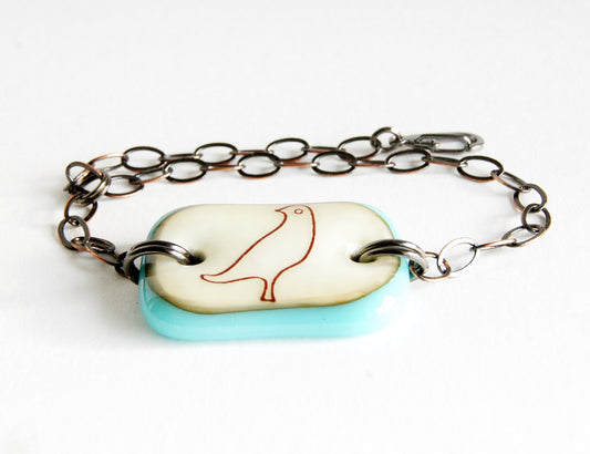 A fused glass bracelet with an illustration of a dove bird.