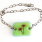 Adjustable chain and glass bracelet with echinacea flower image on green and blue glass. 