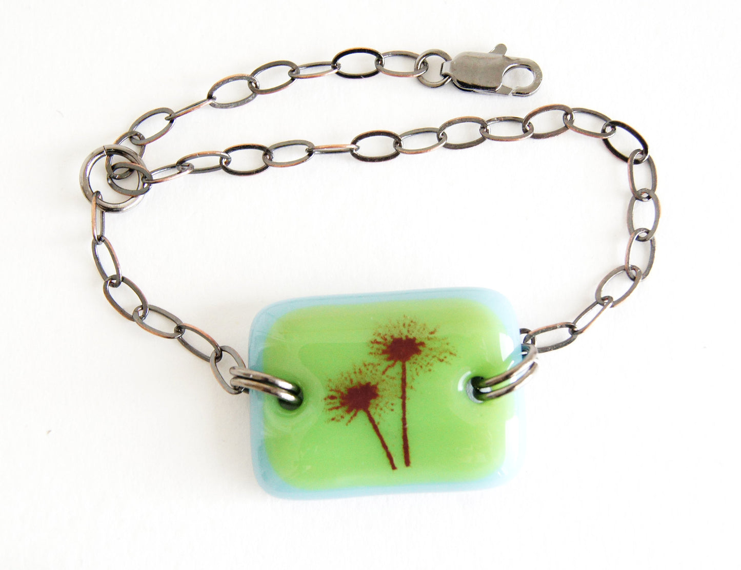 Adjustable chain and glass bracelet with echinacea flower image on green and blue glass. 