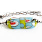 A fun abstract glass bracelet in green and blue with red dots.