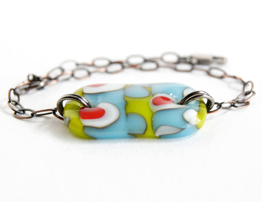 A fun abstract glass bracelet in green and blue with red dots.
