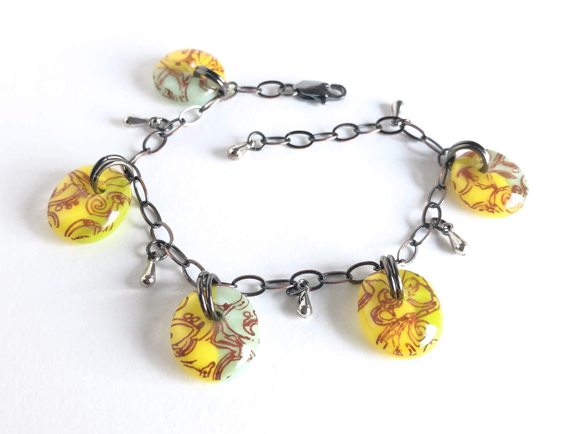 A one of a kind adjustable fused glass bracelet with warm yellow and pastel and light olive green glass drops.