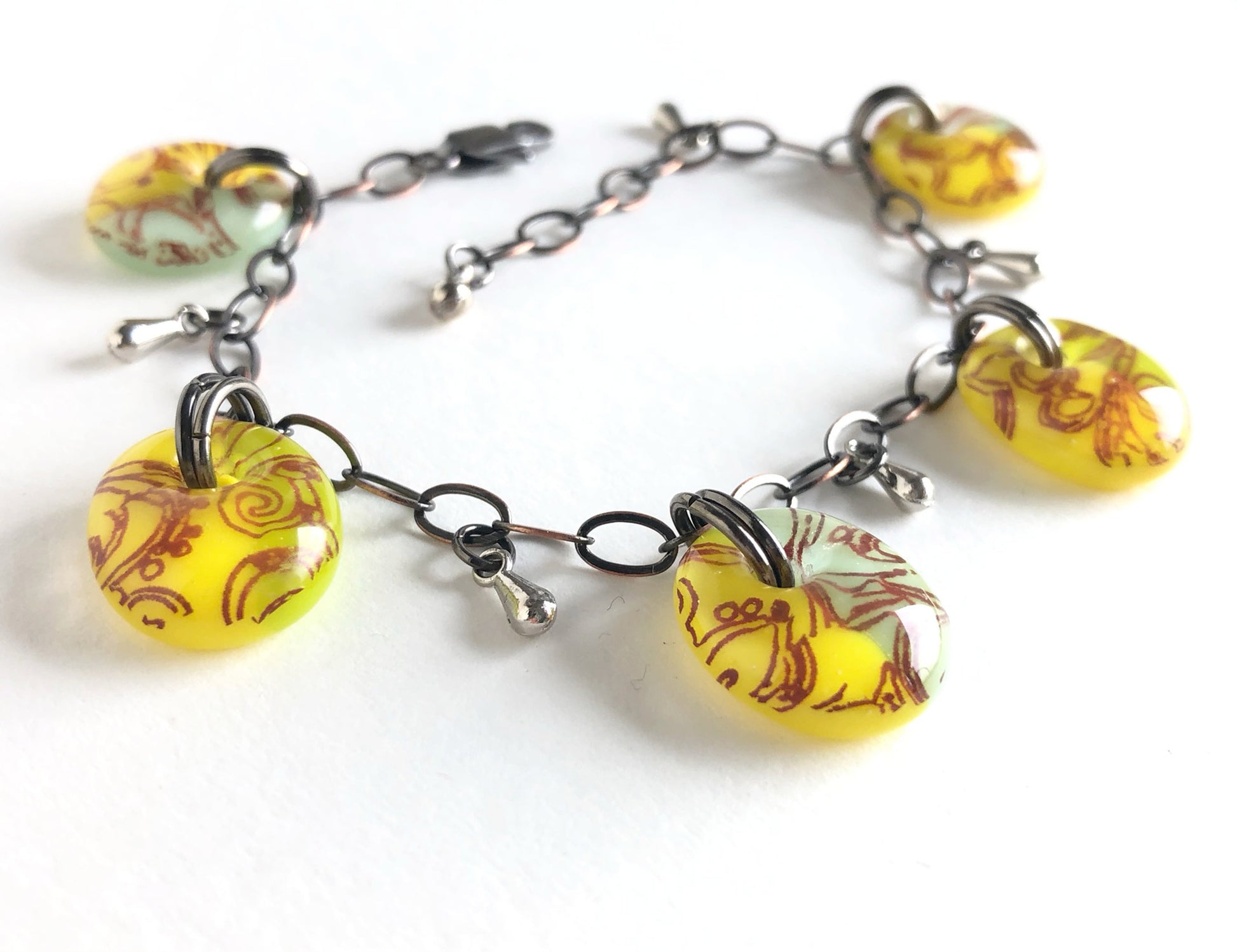 Yellow and green glass charm drop bracelet on bronze chain, handmade by Leila Cools.