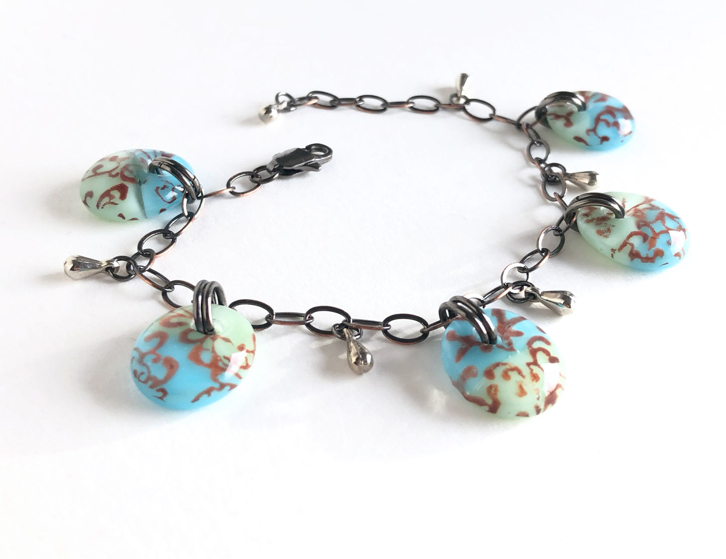 One of a kind adjustable fused glass bracelet with antiqued bronze chain and stainless steel tear drop beads.