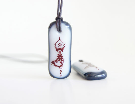 A mandala yoga design on a handmade glass necklace handmade by Leila Cools